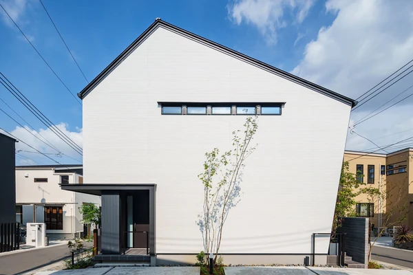 アルネットホームの注文住宅の外観。白い外壁に横長の高窓を配した切妻屋根の住まい
