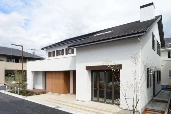 アルネットホームの注文住宅の外観。木製の玄関ドアと白い塗り壁の2階建て