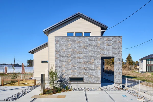 アルネットホームの注文住宅の外観。石張りの壁面と切妻屋根を組み合わせた住まい